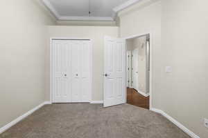 Unfurnished bedroom with carpet floors, ornamental molding, a closet, and baseboards