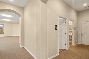 Club House. Hall featuring arched walkways, baseboards, visible vents, and carpet