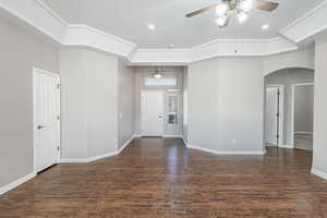 Interior space featuring arched walkways, ceiling fan, baseboards, and wood finished floors