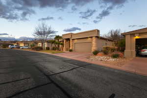 View of front of property with driveway, stone siding, a residential view, and stucco siding