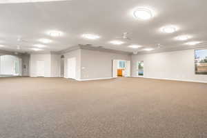 Club House. Empty room with arched walkways, ceiling fan, baseboards, ornamental molding, and carpet