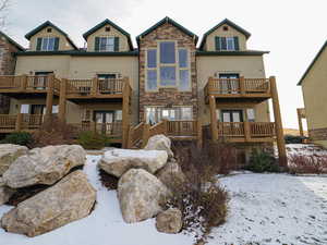 Snow covered house featuring stone siding