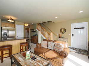 Living room featuring recessed lighting, light colored carpet, baseboards, and stairs