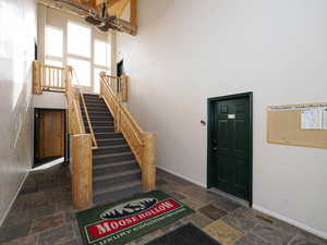 Foyer featuring visible vents, baseboards, a towering ceiling, and stone tile floors