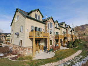 Rear view of property with stone siding, a patio, and a residential view