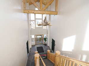 Hallway with an inviting chandelier, a high ceiling, stone finish floor, and stairway