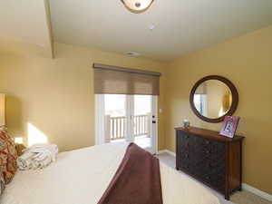 Carpeted bedroom with access to exterior, visible vents, and baseboards