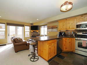 Kitchen featuring a fireplace, tasteful backsplash, appliances with stainless steel finishes, open floor plan, and a peninsula