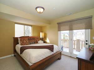 Bedroom with access to outside, visible vents, multiple windows, and light carpet