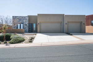 Custom home featuring an attached garage, concrete driveway, stone siding, and stucco siding