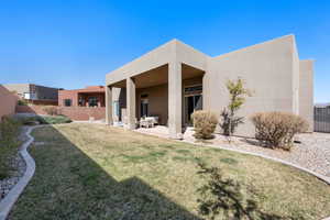 Back of house featuring a lawn, a patio area, fence, and stucco siding