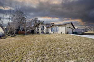 View of front of house featuring an attached garage, brick siding, fence, driveway, and a front yard