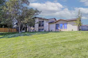 Exterior space with a yard, brick siding, board and batten siding, and fence