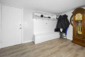 Mudroom with a textured ceiling, baseboards, and wood finished floors