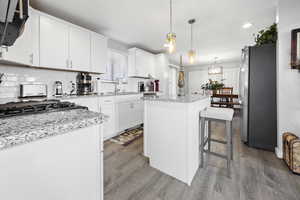 Kitchen featuring a sink, a kitchen island, light wood-type flooring, freestanding refrigerator, and decorative backsplash