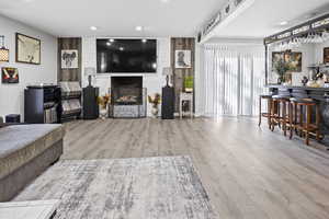 Living area featuring an accent wall, a large fireplace, wood walls, and wood finished floors