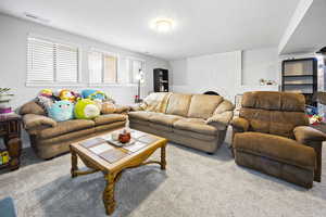 Carpeted living area featuring a fireplace, visible vents, and a textured ceiling