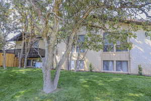 Back of house featuring a yard, fence, and brick siding