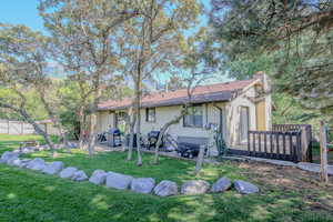 Back of house featuring a deck, a patio, fence, a yard, and a chimney