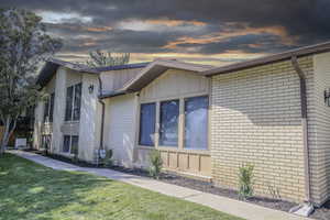 View of front of house with brick siding, board and batten siding, and a yard