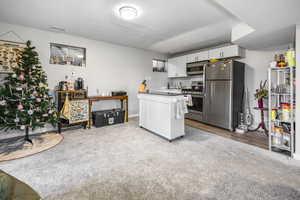 Kitchen with dark countertops, visible vents, appliances with stainless steel finishes, white cabinets, and a textured ceiling