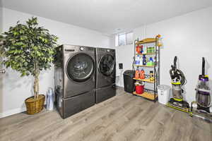 Laundry room with a textured ceiling, laundry area, washer and clothes dryer, and wood finished floors