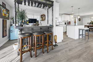 Kitchen with a kitchen breakfast bar, white cabinets, a kitchen island, and light wood finished floors