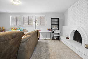 Living area featuring a brick fireplace, carpet, visible vents, and baseboards