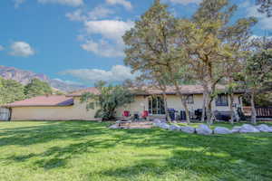 Rear view of property featuring a mountain view, a patio area, brick siding, and a lawn