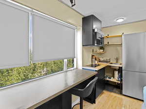 Kitchen featuring freestanding refrigerator, open shelves, light wood-style floors, a desk, and black electric stovetop