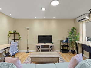 Living room featuring a wall mounted AC, wood finished floors, and recessed lighting