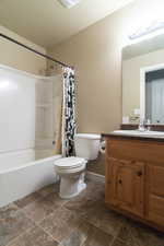 Bathroom featuring toilet, shower / bathtub combination with curtain, and vanity