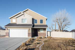 View of front of property featuring an attached garage, fence, concrete driveway, and brick siding