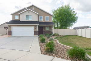View of front of property with brick siding, an attached garage, fence, and a porch