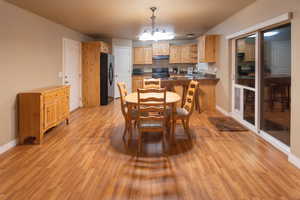 Dining space with a notable chandelier, light wood-style flooring, and baseboards