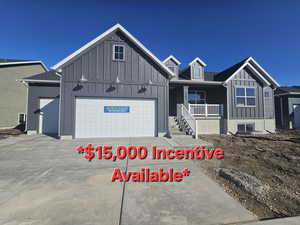 View of front of property with a garage, driveway, board and batten siding, and covered porch