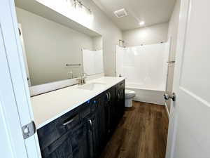 Bathroom featuring visible vents, toilet, wood finished floors, vanity, and shower / bathing tub combination