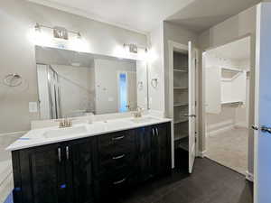 Bathroom featuring double vanity, a spacious closet, tile patterned flooring, and a sink