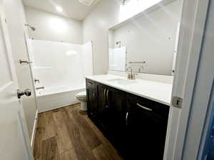 Full bathroom with visible vents, shower / bathing tub combination, toilet, vanity, and wood finished floors