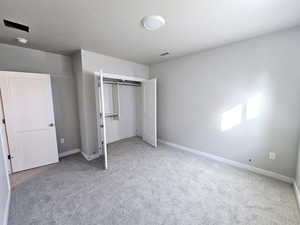 Unfurnished bedroom featuring carpet, visible vents, baseboards, and a closet