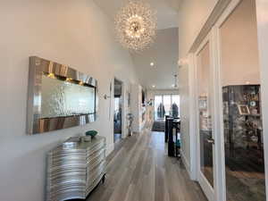 Hall with baseboards, a towering ceiling, an inviting chandelier, LVP  floor, and recessed lighting