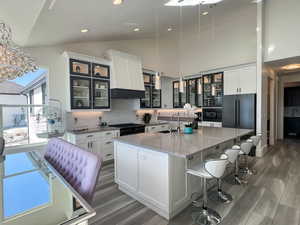 Kitchen with light LVP flooring, black appliances, decorative backsplash, and a sink