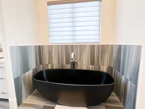 Full bath with a freestanding tub, tile walls, and a sink