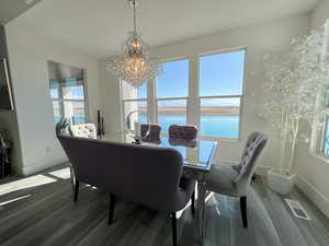 Dining area with baseboards, visible vents, wood LVP floors, a water view, and a chandelier