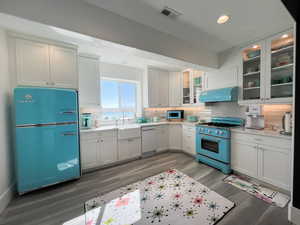 Kitchen with white dishwasher, under cabinet range hood,, fridge, and high end range