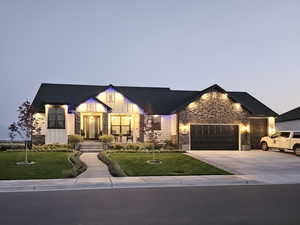 View of front of home with a garage, concrete driveway, stone siding, a front lawn, and board and batten siding