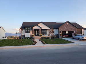 View of front of house with board and batten siding, concrete driveway, a yard, and a garage