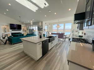 Kitchen featuring LVP floor, white cabinets, a sink, and dishwashing machine