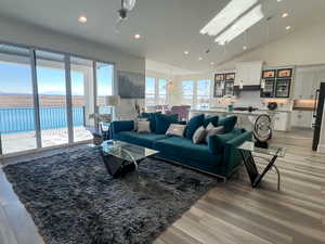 Living area featuring light LVP flooring, high vaulted ceiling, and recessed lighting