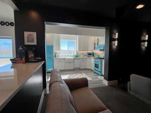 Kitchen featuring under cabinet range hood, a sink, white cabinetry, appliances with stainless steel finishes, and backsplash